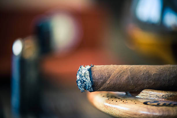 smoking cigar close up view, in wooden ashtray