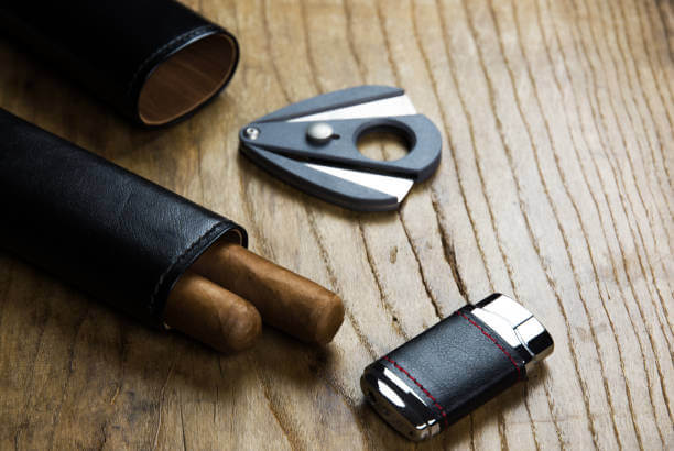 Leather case with cigars, lighter and cigar cutter on an old wooden board